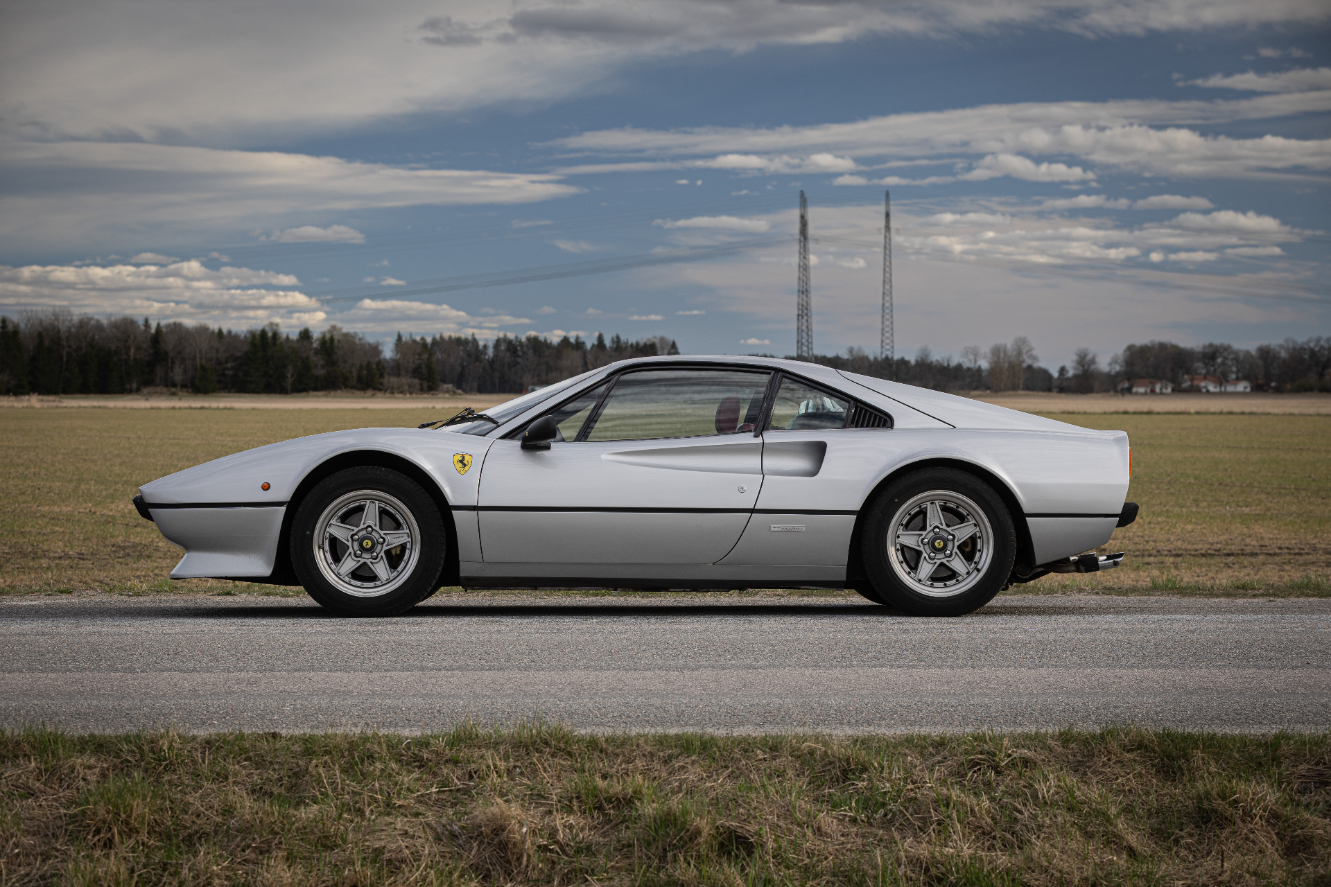 Ferrari 308 GTB side profile in front of open field